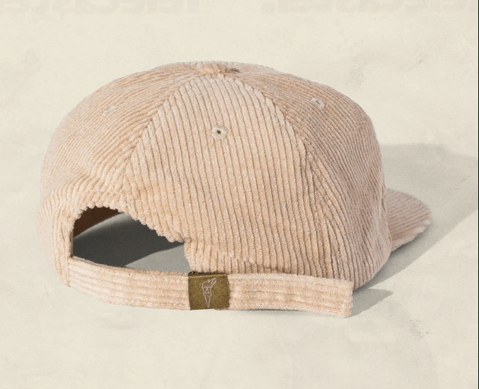 Tan corduroy cap on a light beige background, back view