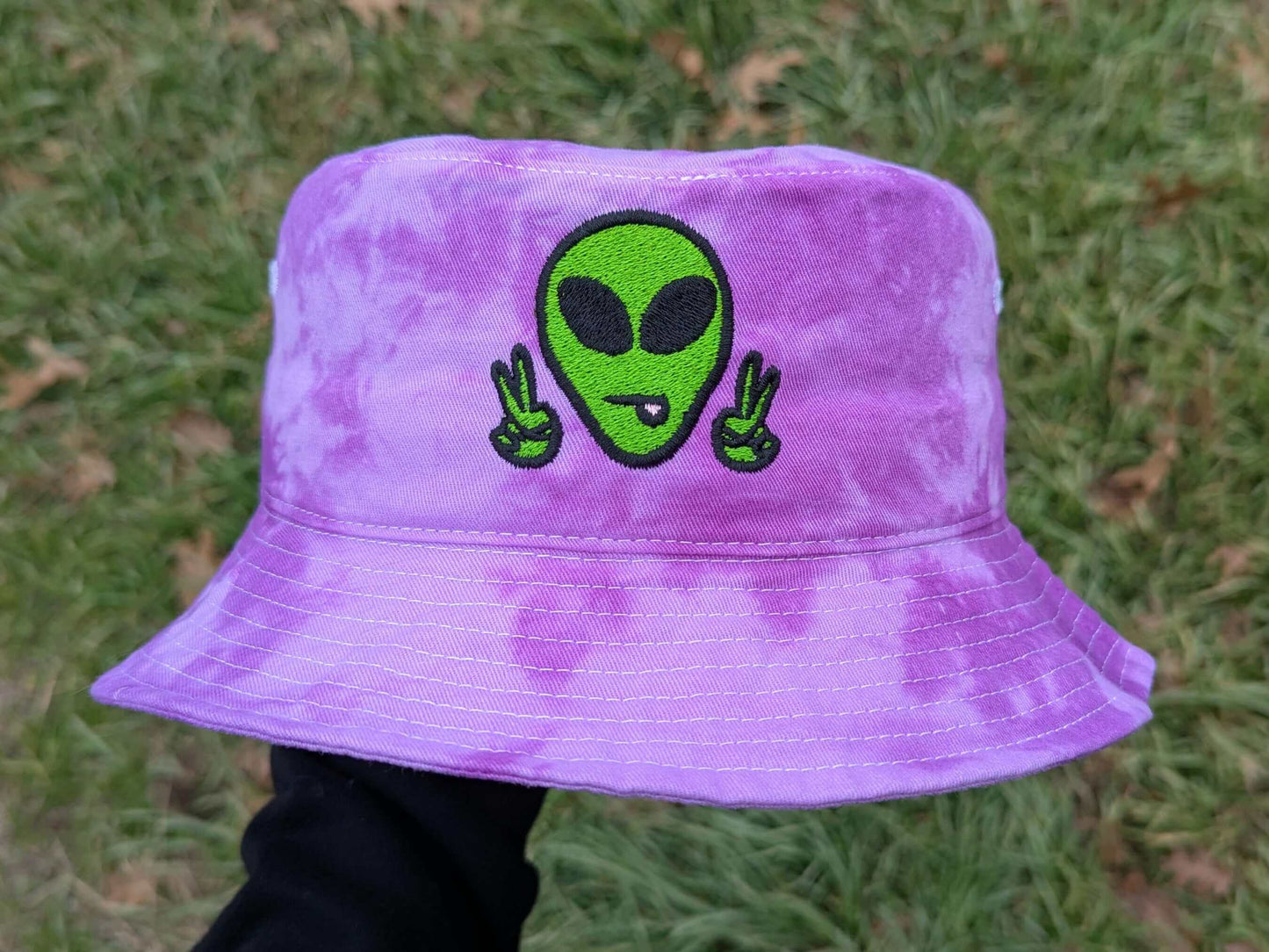 Purple tie-dye bucket hat with a green alien design.