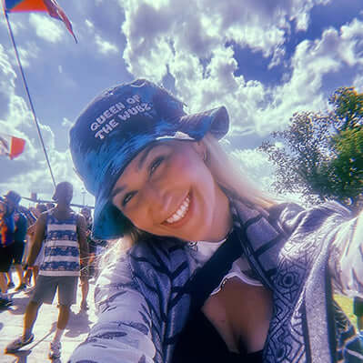 Person wearing a tie dye festival bucket hat Queen Of The Wubz rave accessory bass music embroidered womens hat