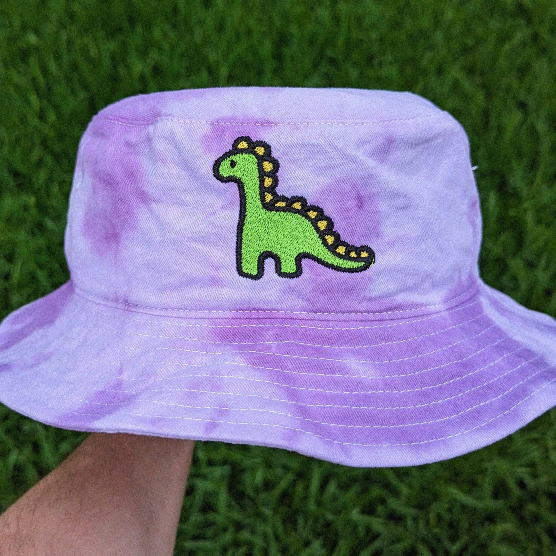 Purple tie-dye bucket hat with a green dinosaur design