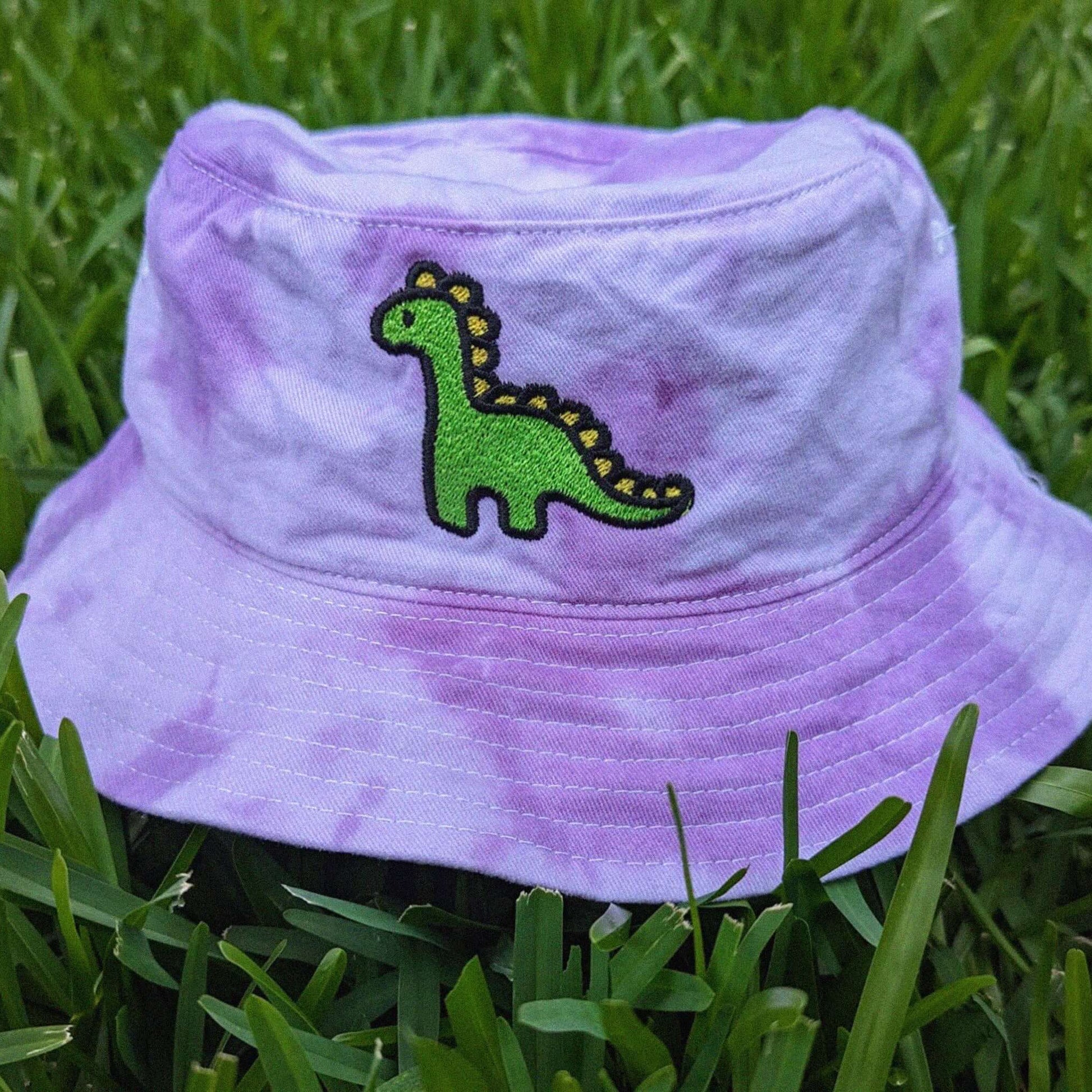 Purple tie-dye bucket hat with a green dinosaur embroidered design