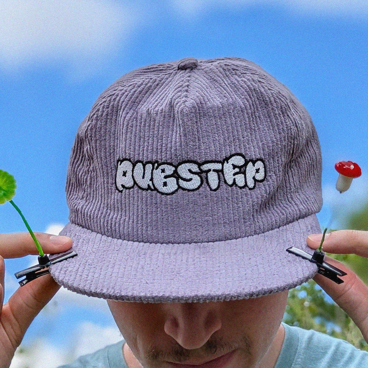 A person outdoors wearing a light purple corduroy baseball cap with 'DUBSTEP' embroidered on the front.