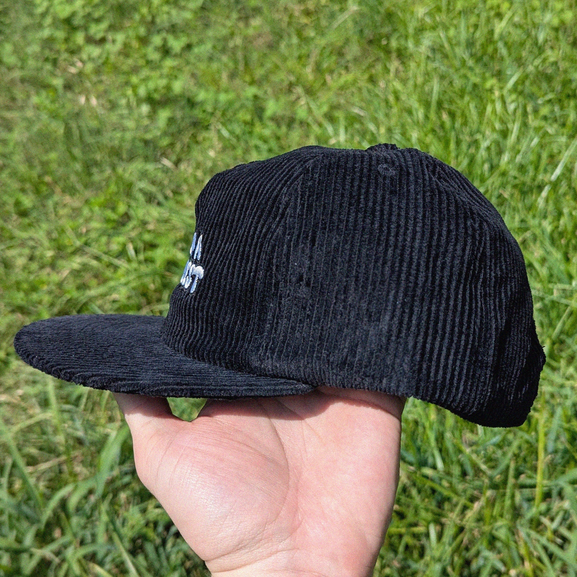 Side video of a black corduroy cap with 'I'm on a sidequest' embroidery