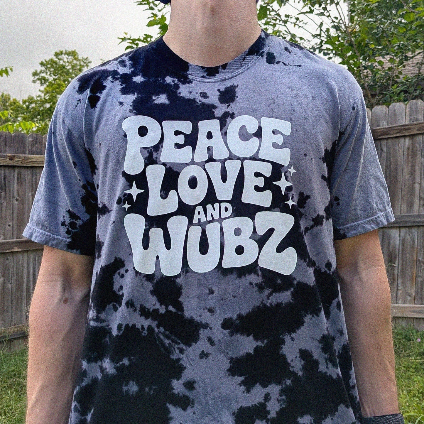 Person wearing a tie-dye t-shirt with 'Peace Love and Wubz' text