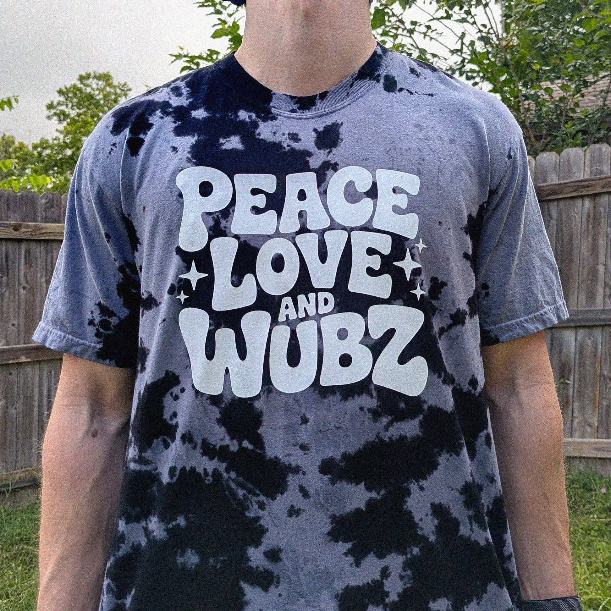 Person wearing a tie-dye t-shirt with 'Peace Love and Wubz' text