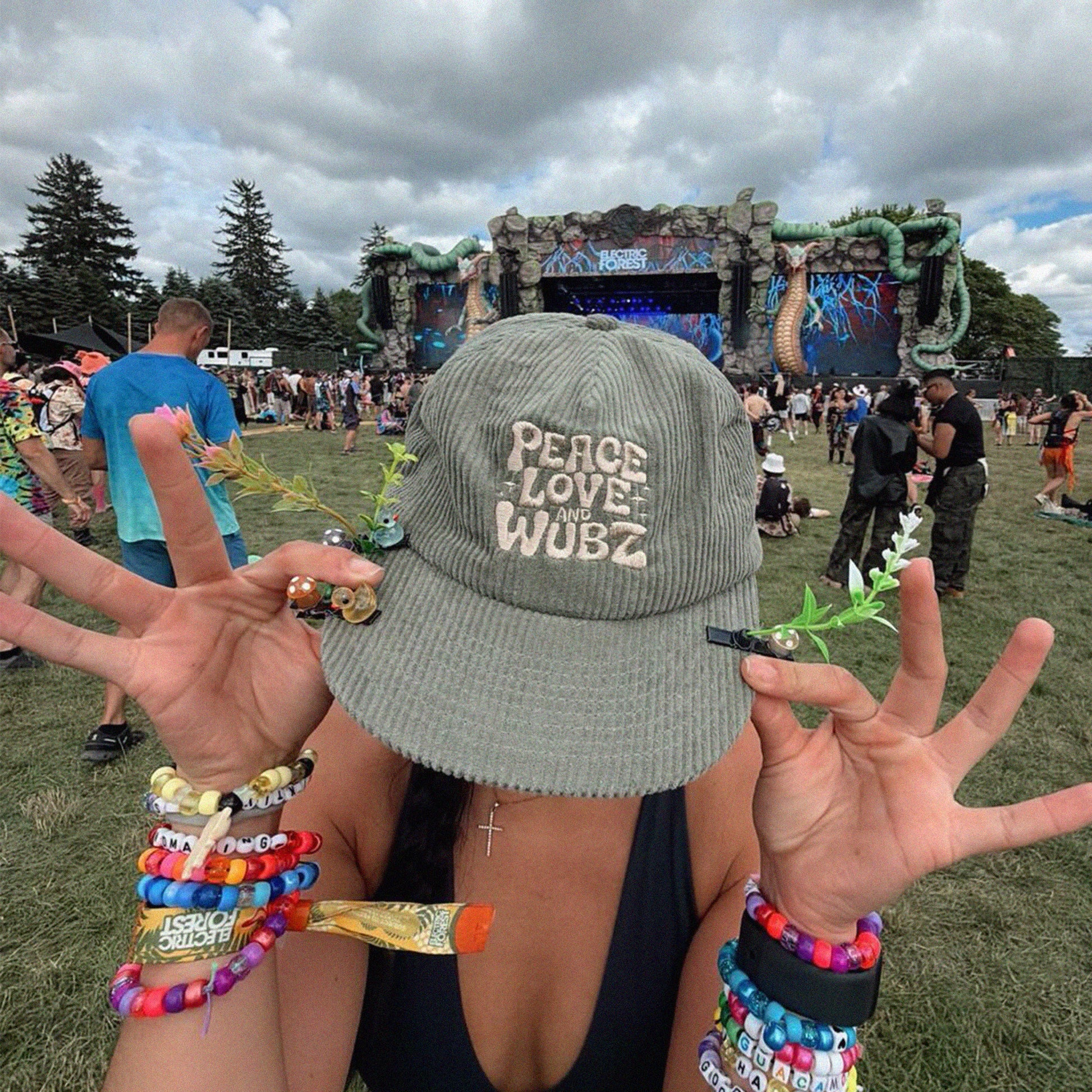 Person wearing a 'Peace Love Wubz' cap at the music festival electric forest